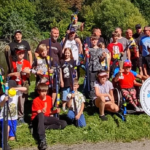 Zwycięzcy zawodów spławikowych pozują z nagrodami na tle parku Kasprowicza