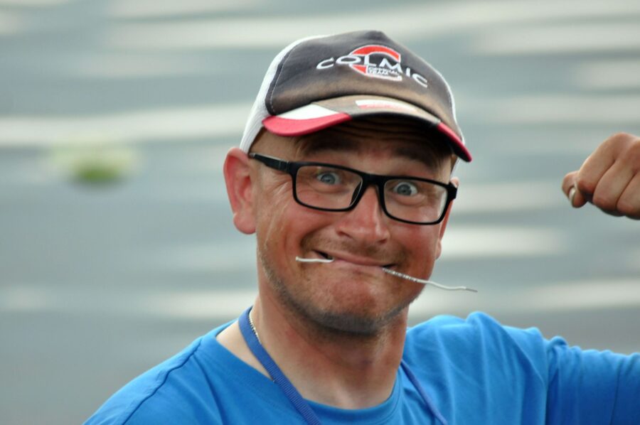 Uśmiechnięty wędkarz nad&nbsp;wodą pokazujący gest sukcesu – zdjęcie ilustracyjne do&nbsp;artykułu o&nbsp;pasji gwiazd i&nbsp;celebrytów.